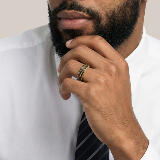 Man wearing a white shirt and striped tie with a gold ring on his finger.