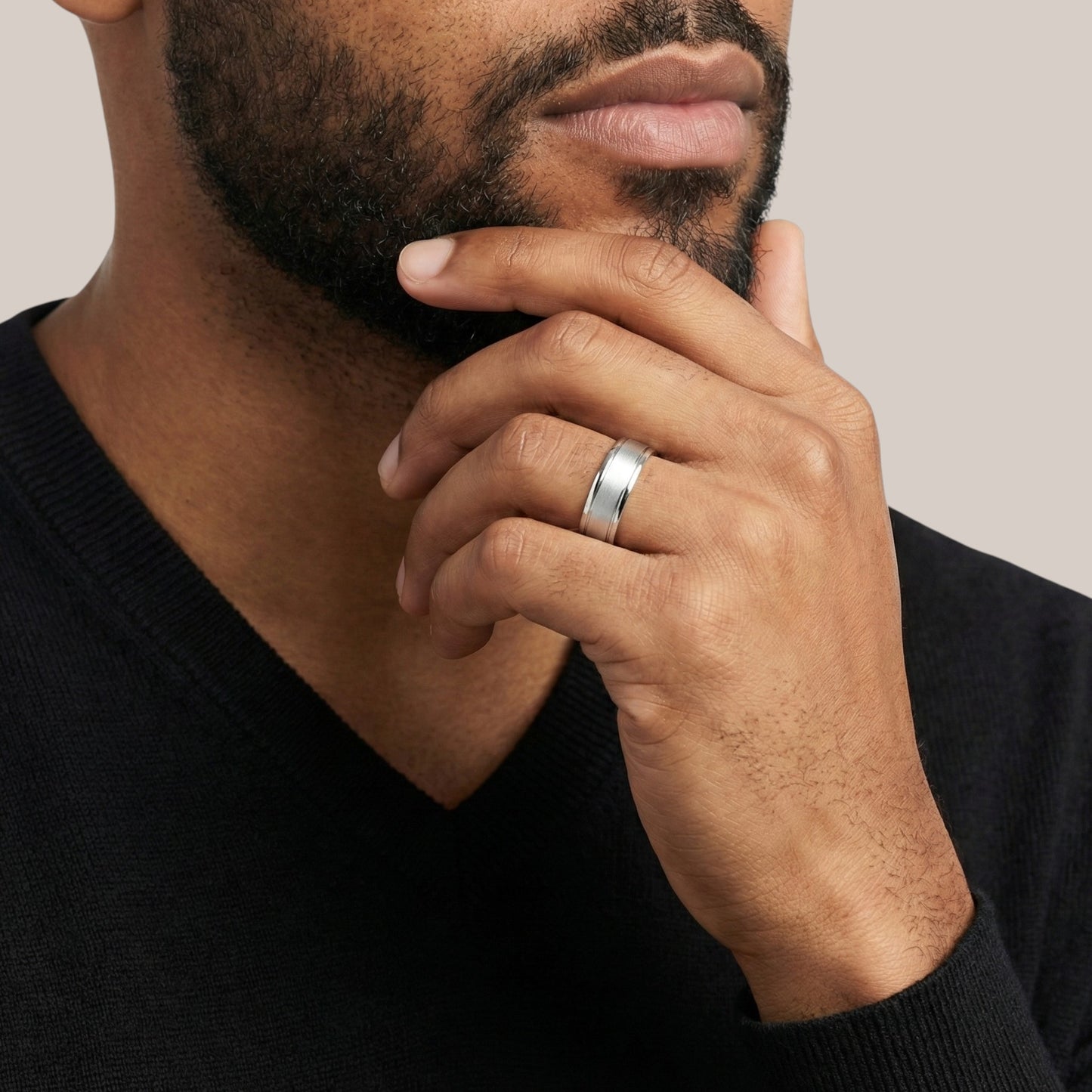 Man wearing a silver ring on his finger with a neutral background