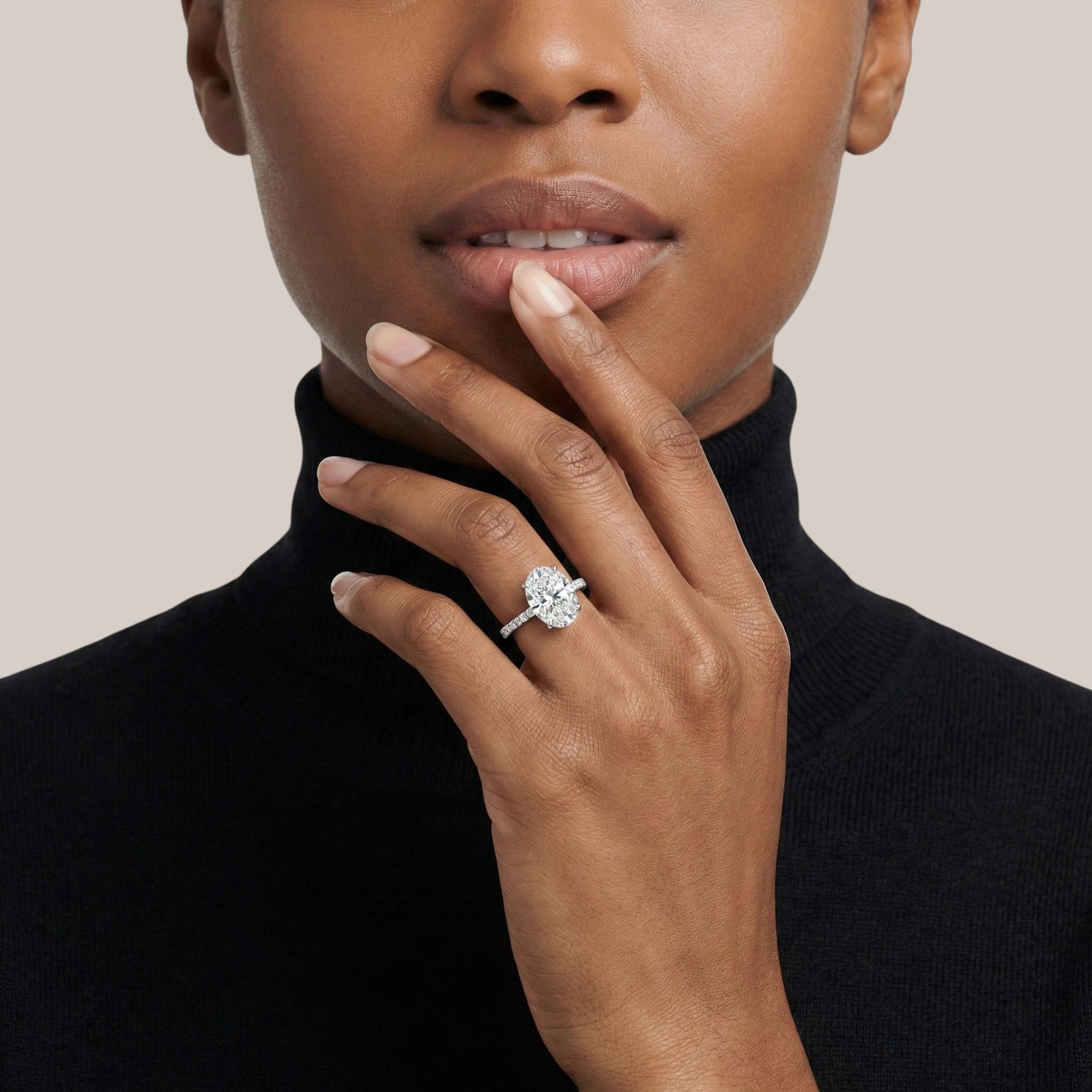 Close-up of a person wearing a diamond ring on a plain background