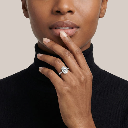 Close-up of a person wearing a diamond ring on a plain background