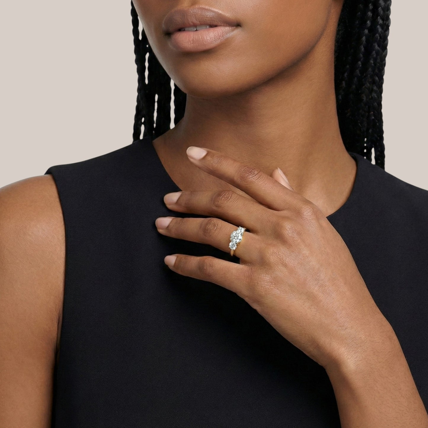 Woman wearing a black sleeveless top with a close-up of her hand and ring.