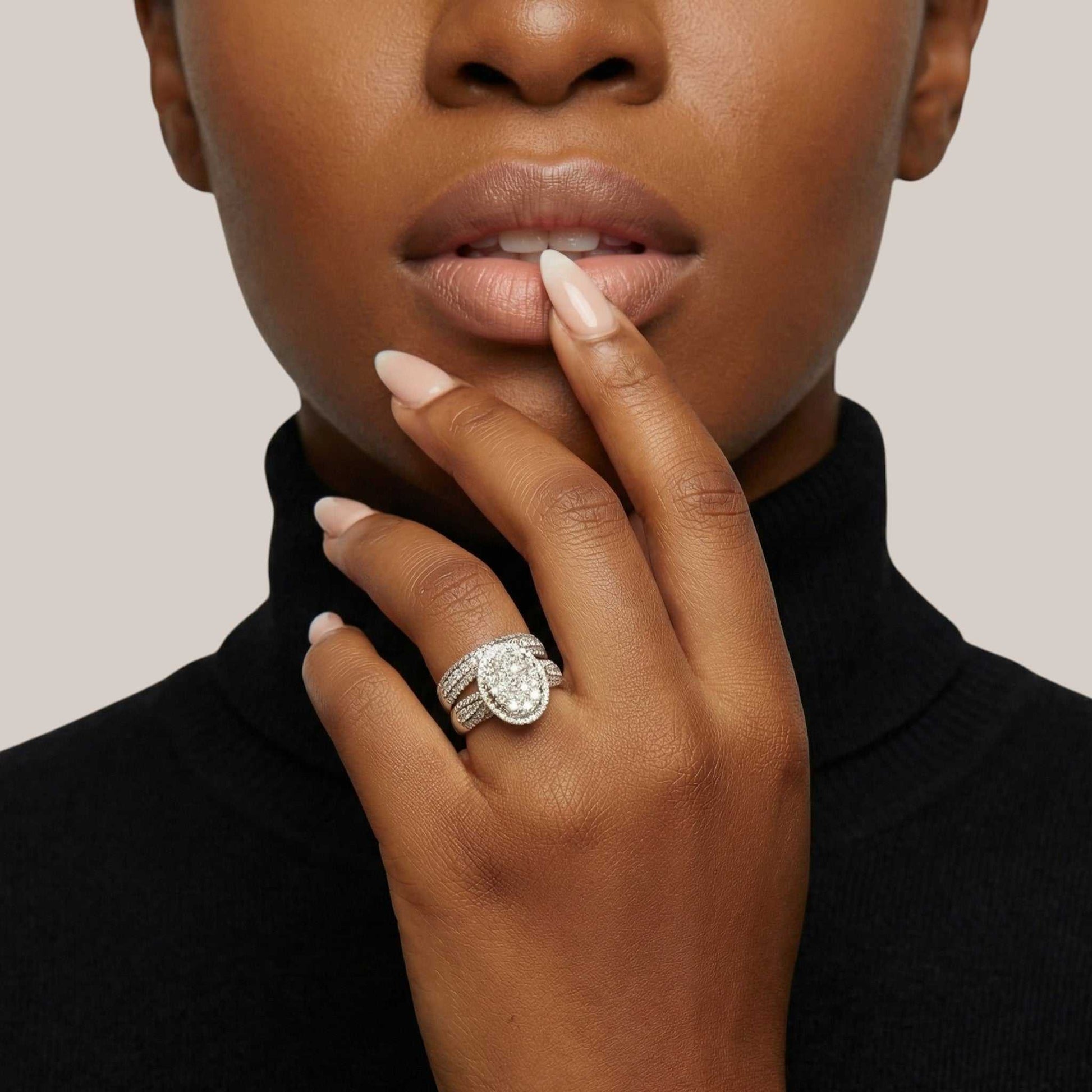 Close-up of a woman's hand wearing a diamond ring with a neutral background