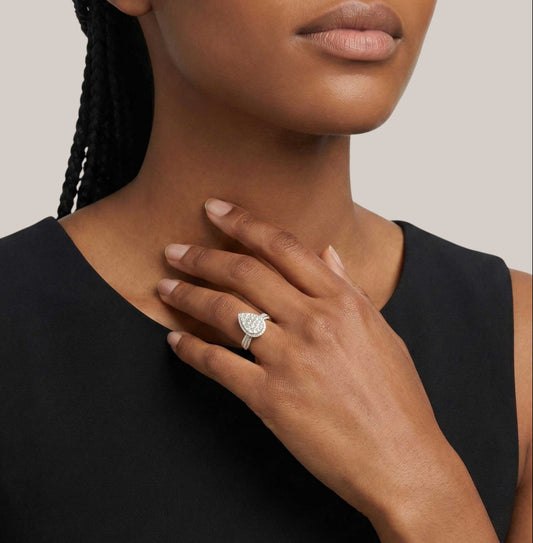 Woman wearing a silver ring with a heart-shaped diamond on a neutral background