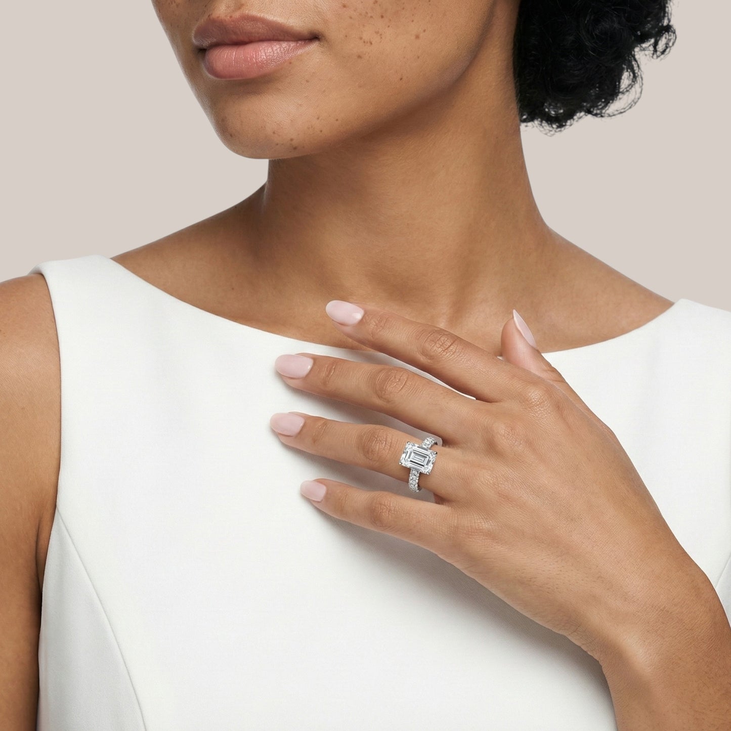 Woman wearing a diamond ring on her hand against a neutral background