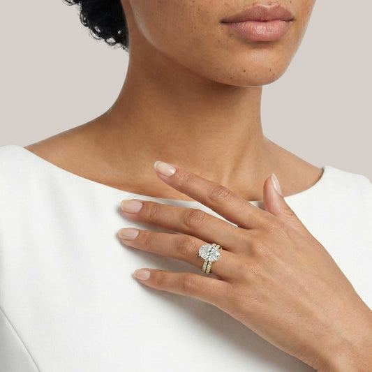 Close-up of a woman's hand wearing a diamond ring on a plain background