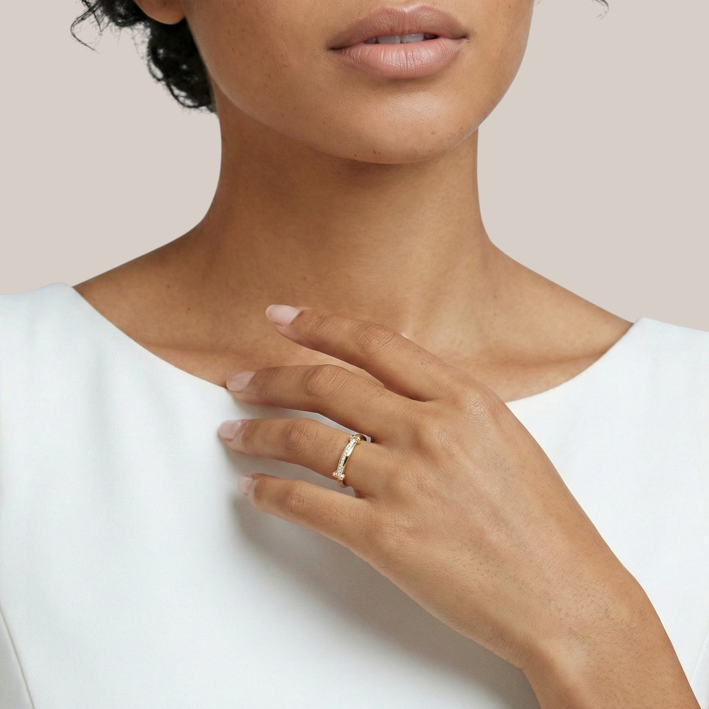 Close-up of a person wearing a gold ring on a plain background