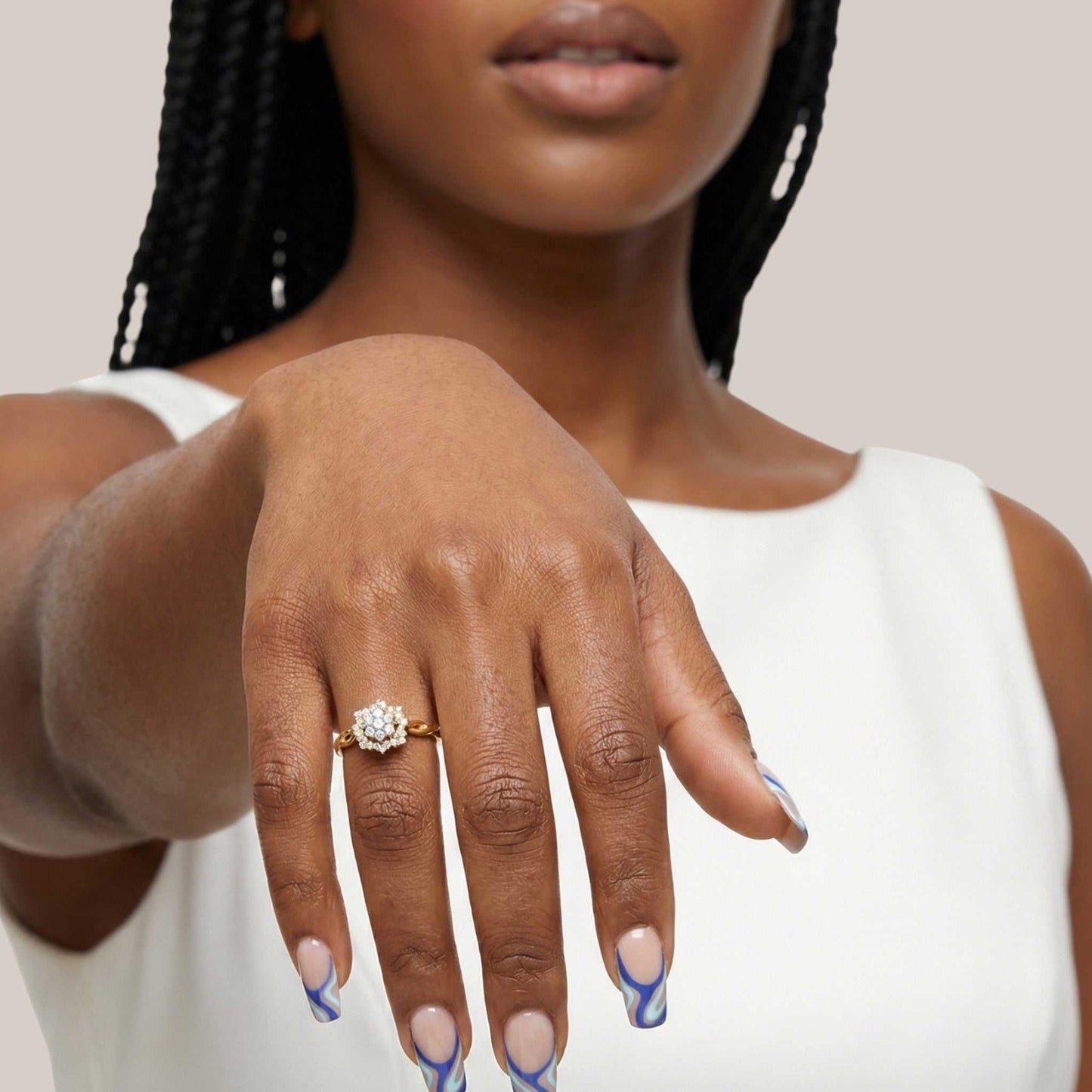 Woman wearing a gold ring with a diamond on her hand against a neutral background