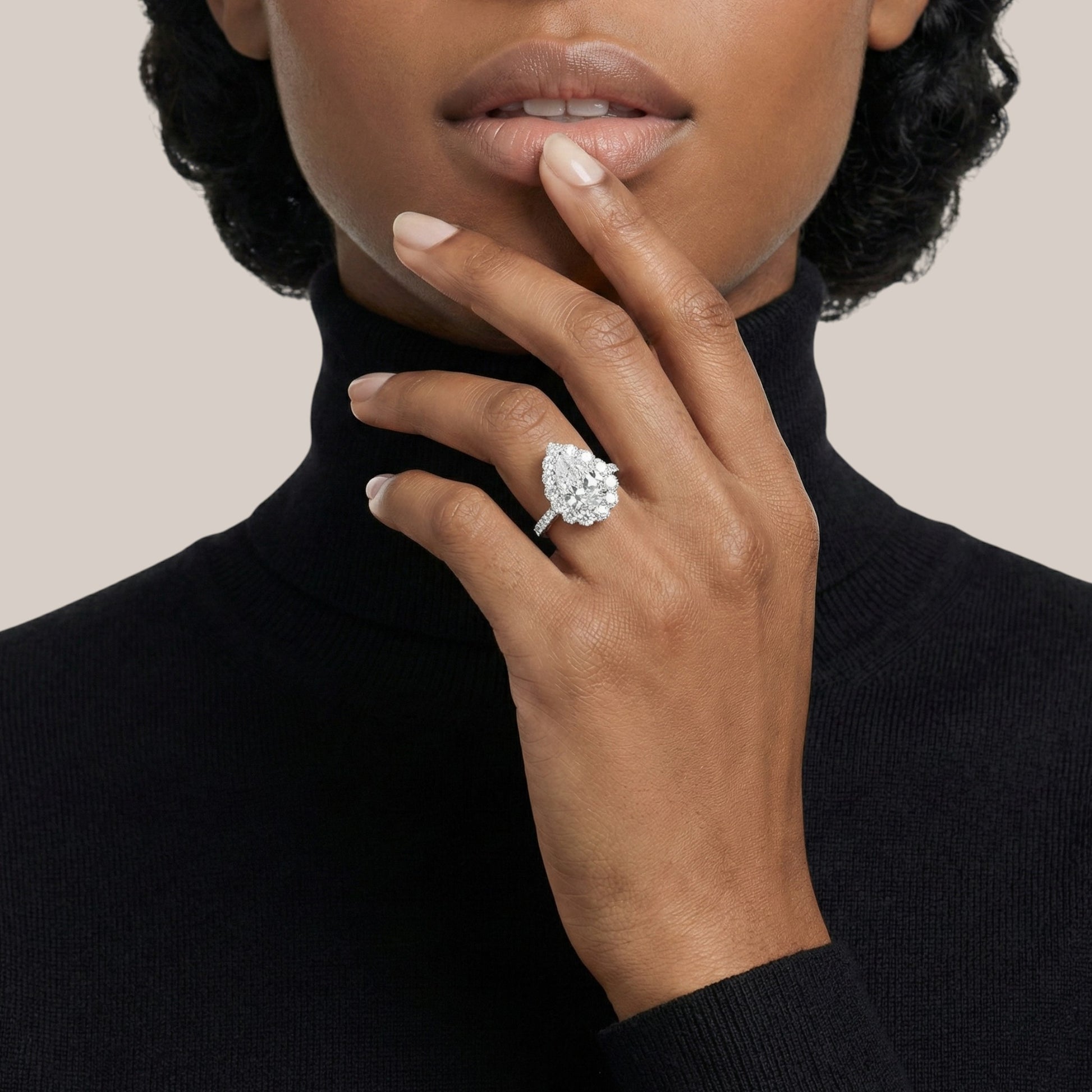 Woman wearing a diamond ring on her finger against a neutral background