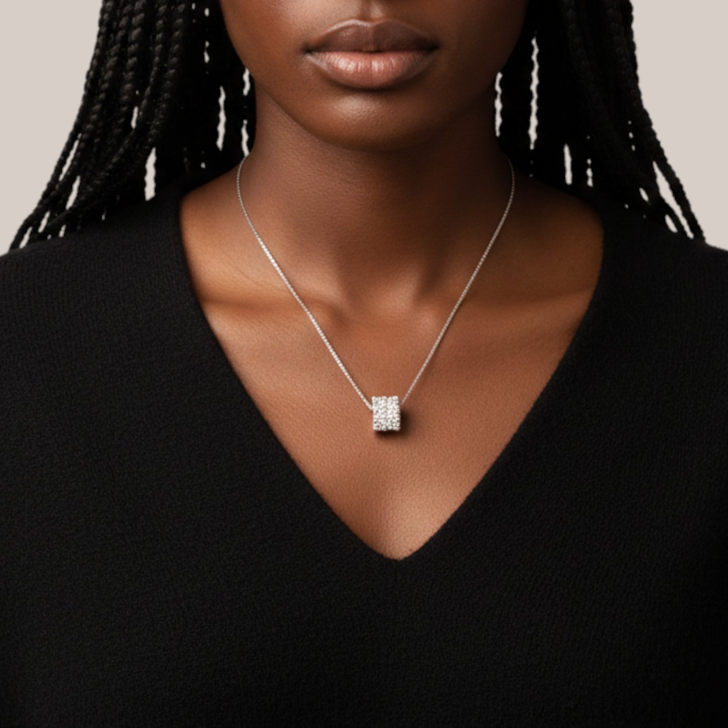 Necklace with a square pendant worn by a person against a neutral background