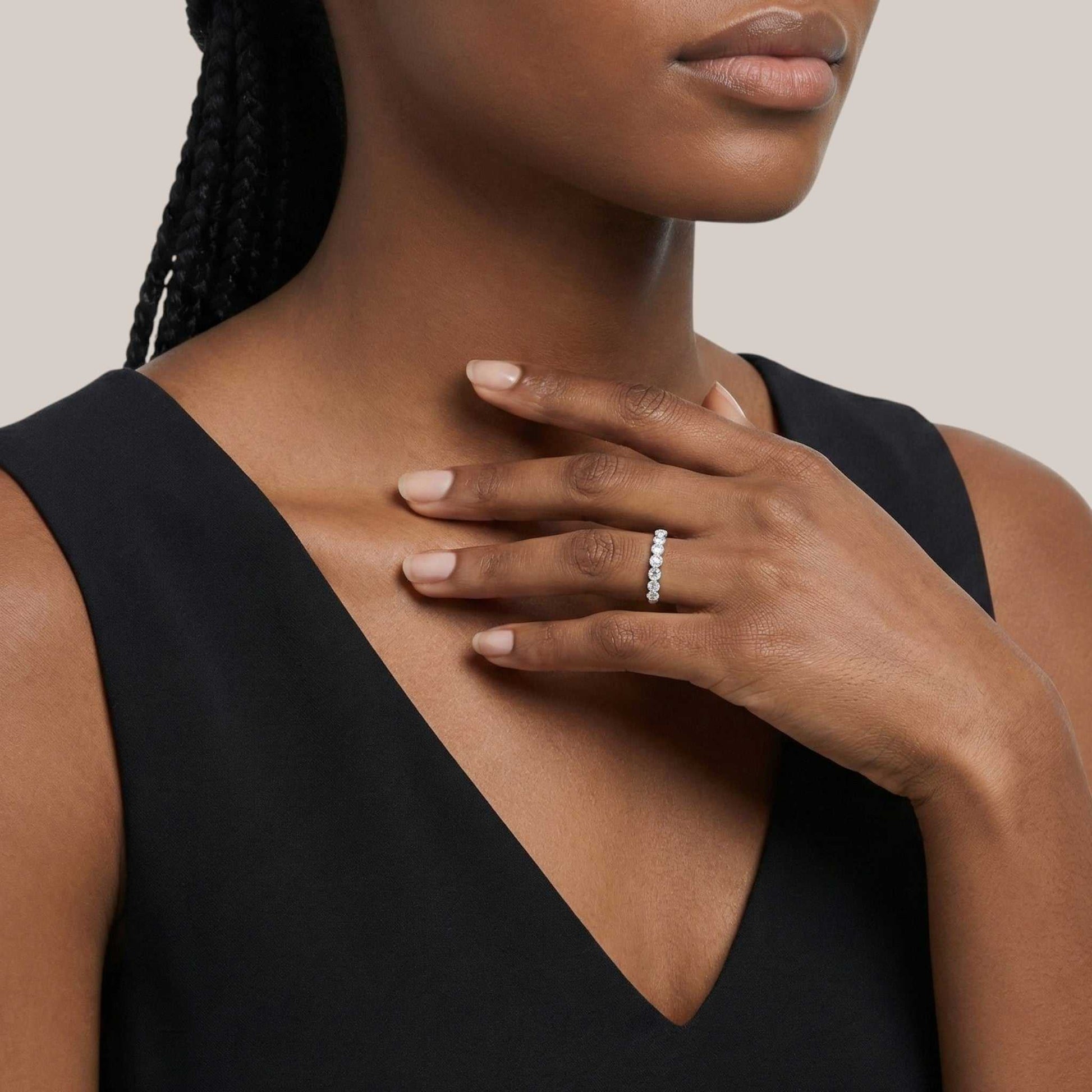 Woman wearing a black sleeveless top with a close-up of her hand and ring.