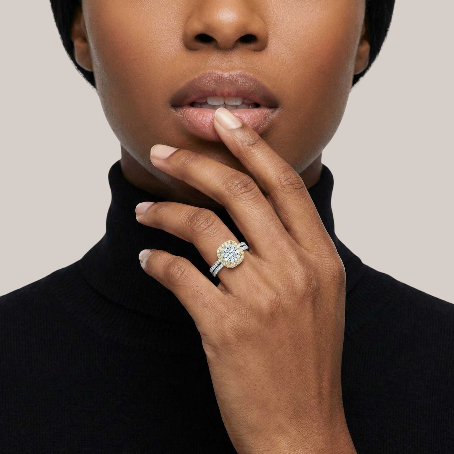 Close-up of a hand wearing a diamond ring with a neutral background