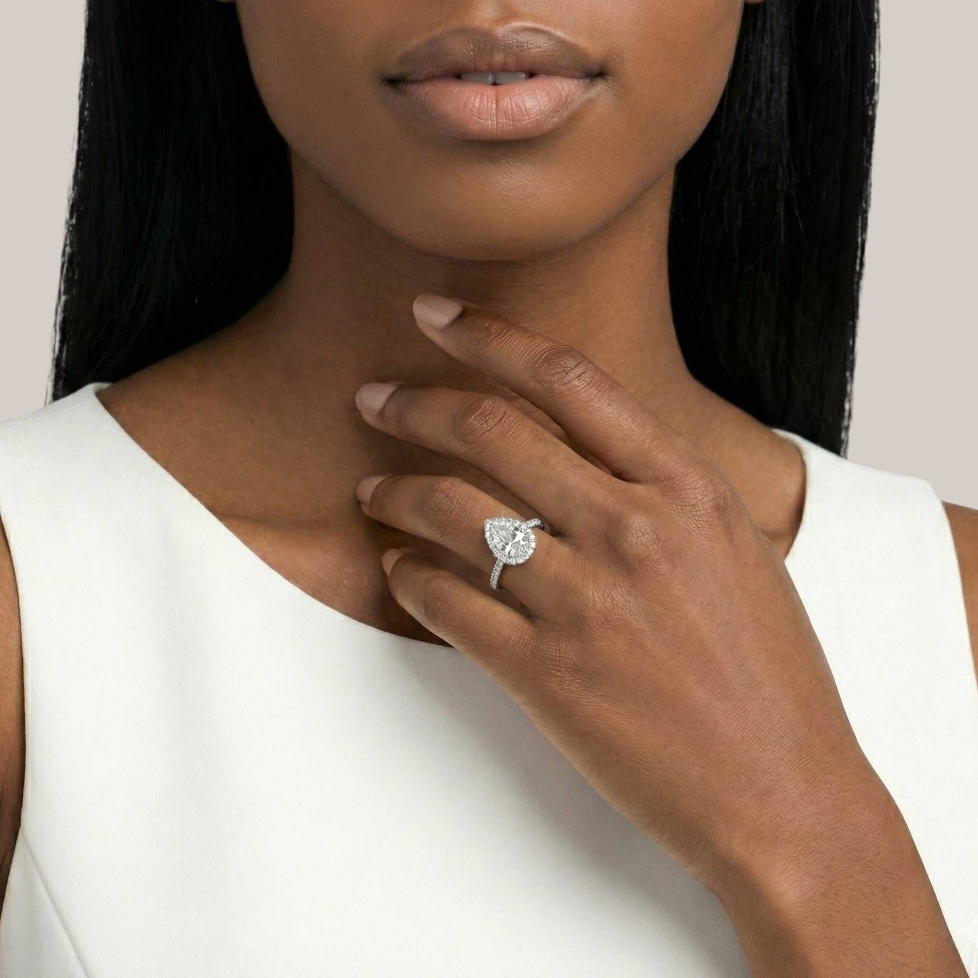Woman wearing a diamond ring on her hand with a plain background