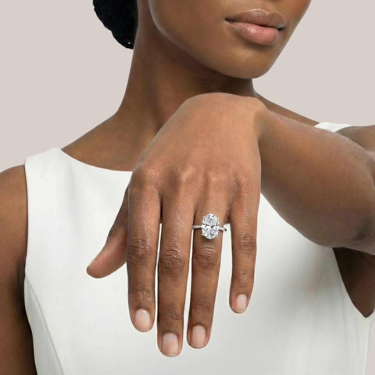 Woman wearing a diamond ring on her hand against a neutral background