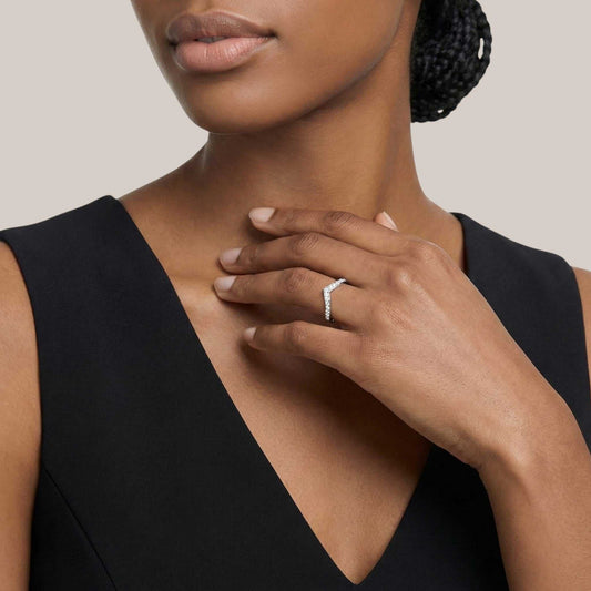 Woman wearing a black dress with a close-up of her hand and ring on a neutral background