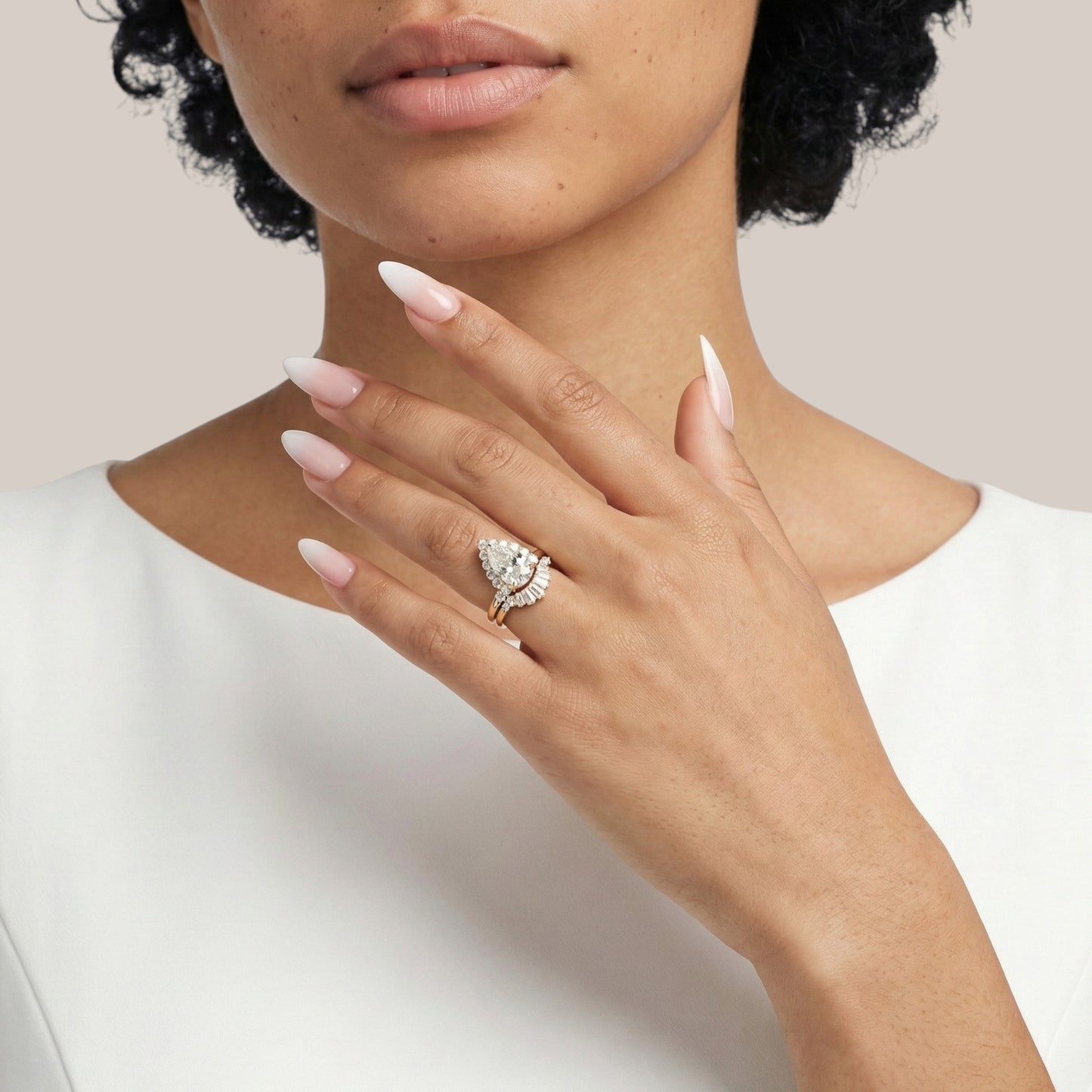 Close-up of a hand wearing a diamond ring with a plain background