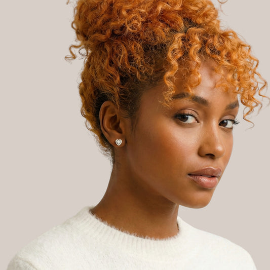Woman with styled hair wearing a white sweater against a neutral background