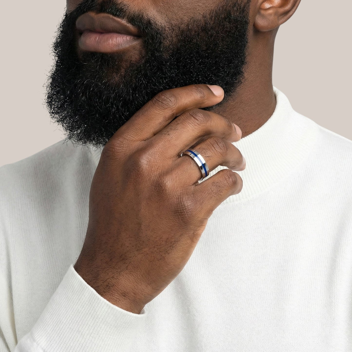 Man wearing a silver ring on his finger with a neutral background