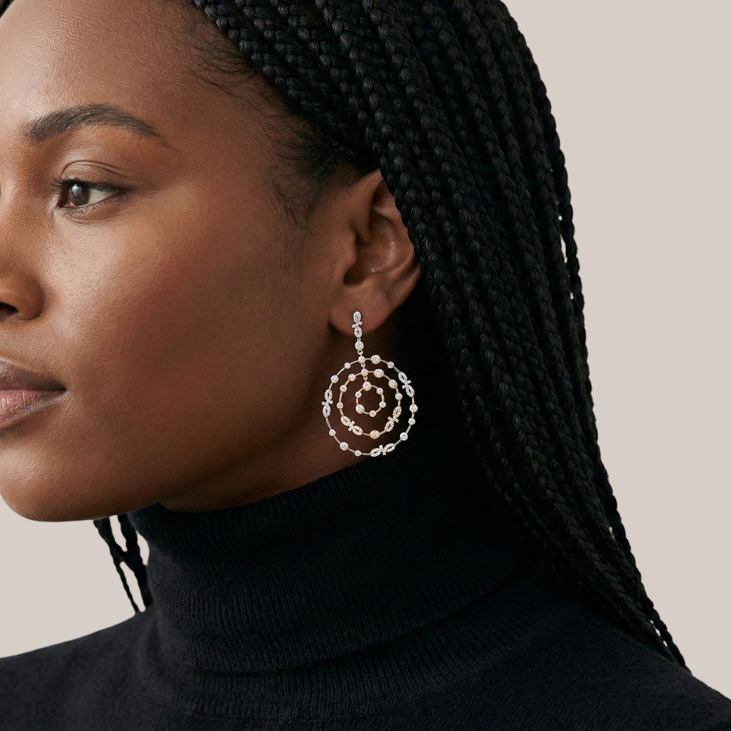 Woman wearing a pair of spiral earrings with a neutral background