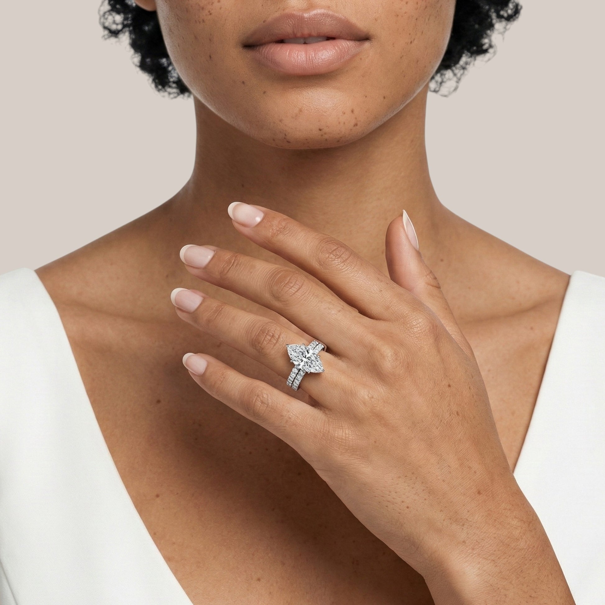 Woman wearing a silver ring with a diamond on a neutral background
