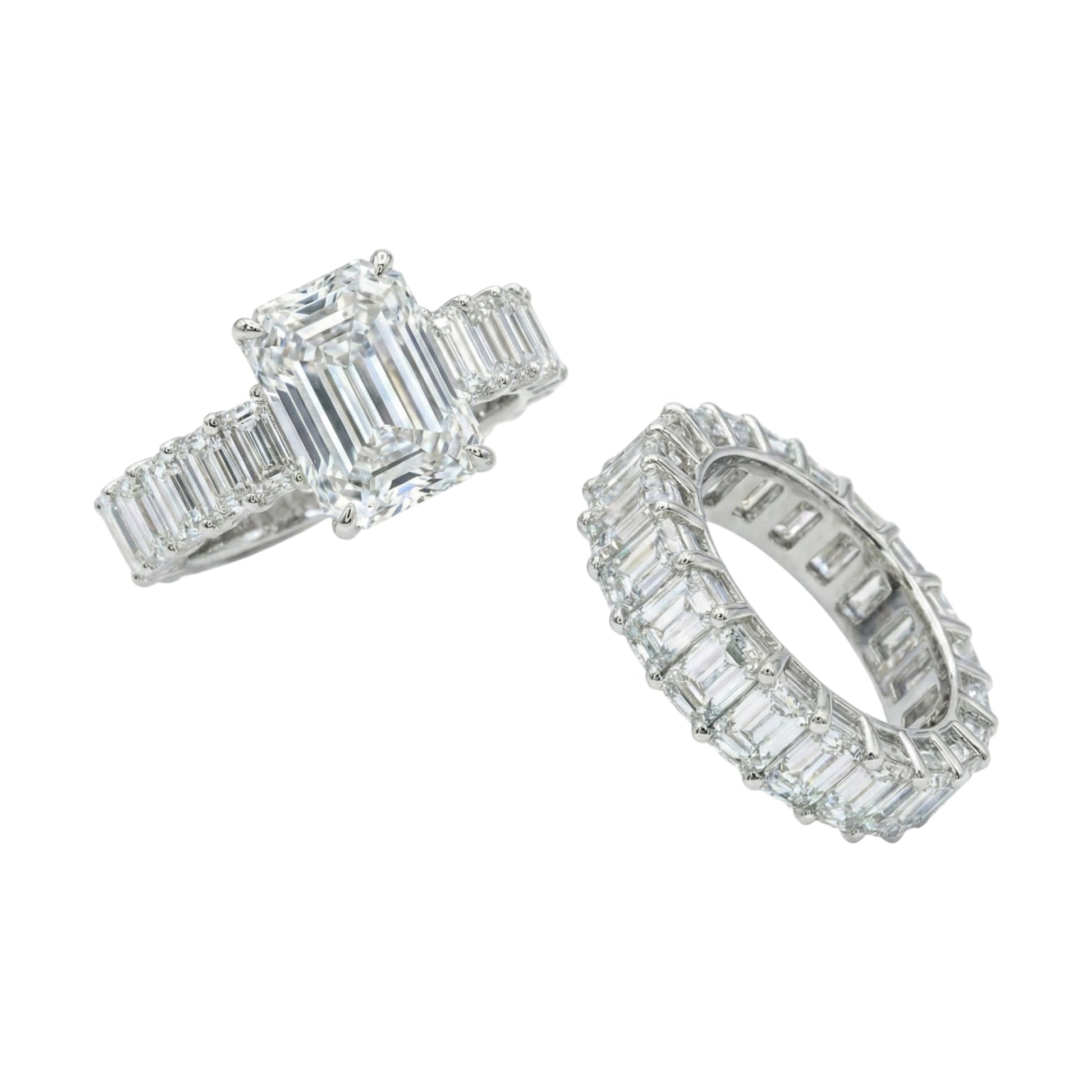 Two diamond rings with emerald-cut stones on a white background