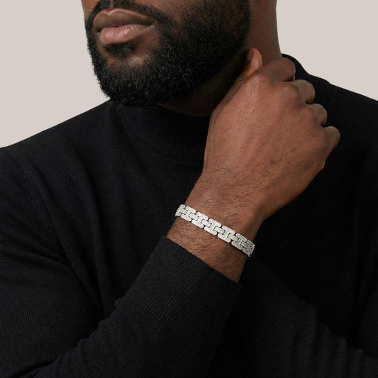 Man wearing a silver bracelet on his wrist against a neutral background