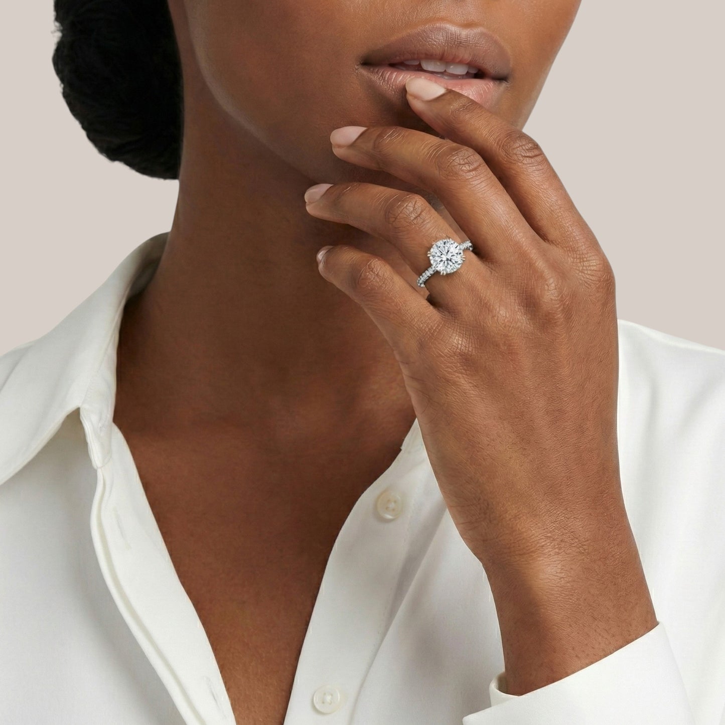 Close-up of a person wearing a diamond ring on a plain background