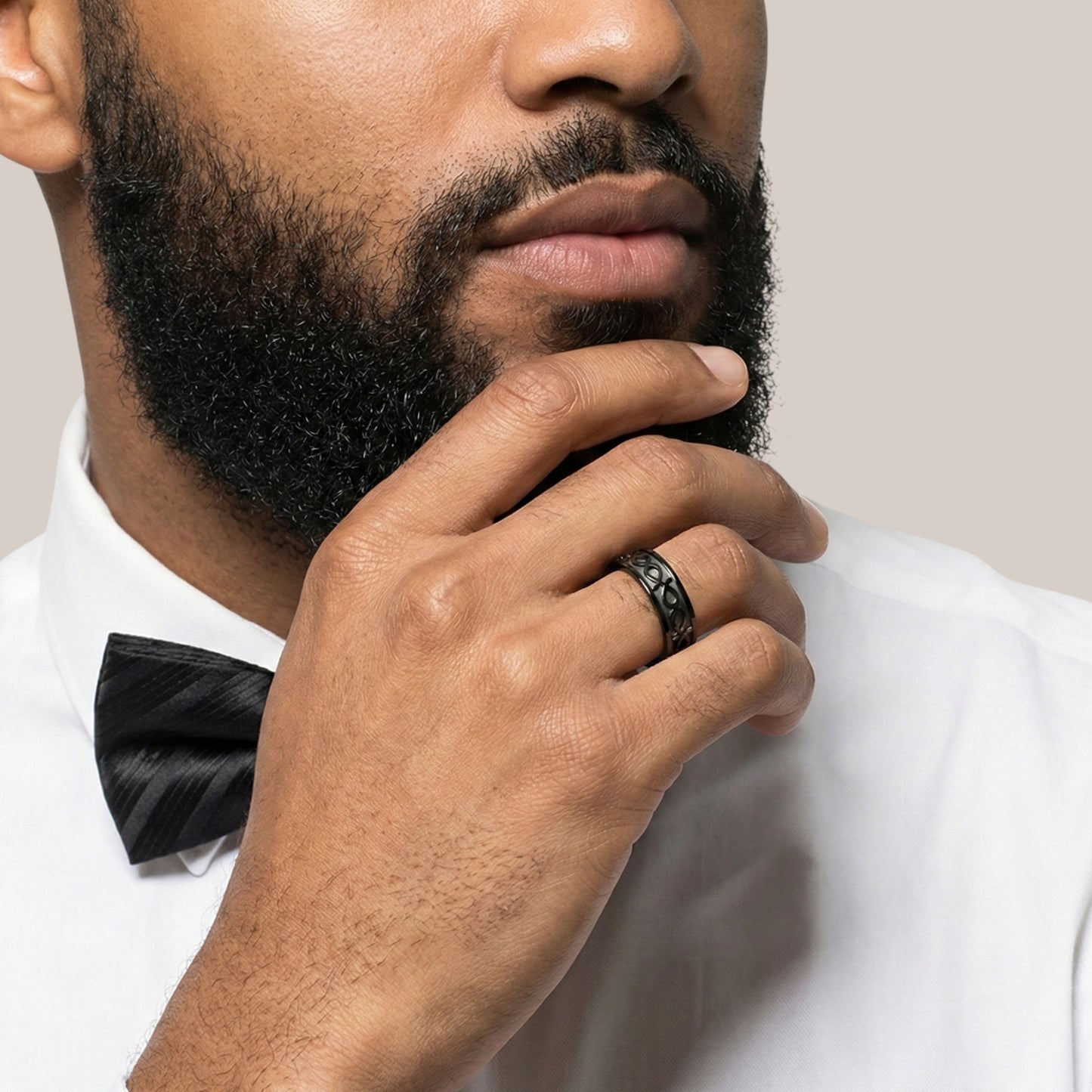Man wearing a white shirt and black bow tie with a neutral background