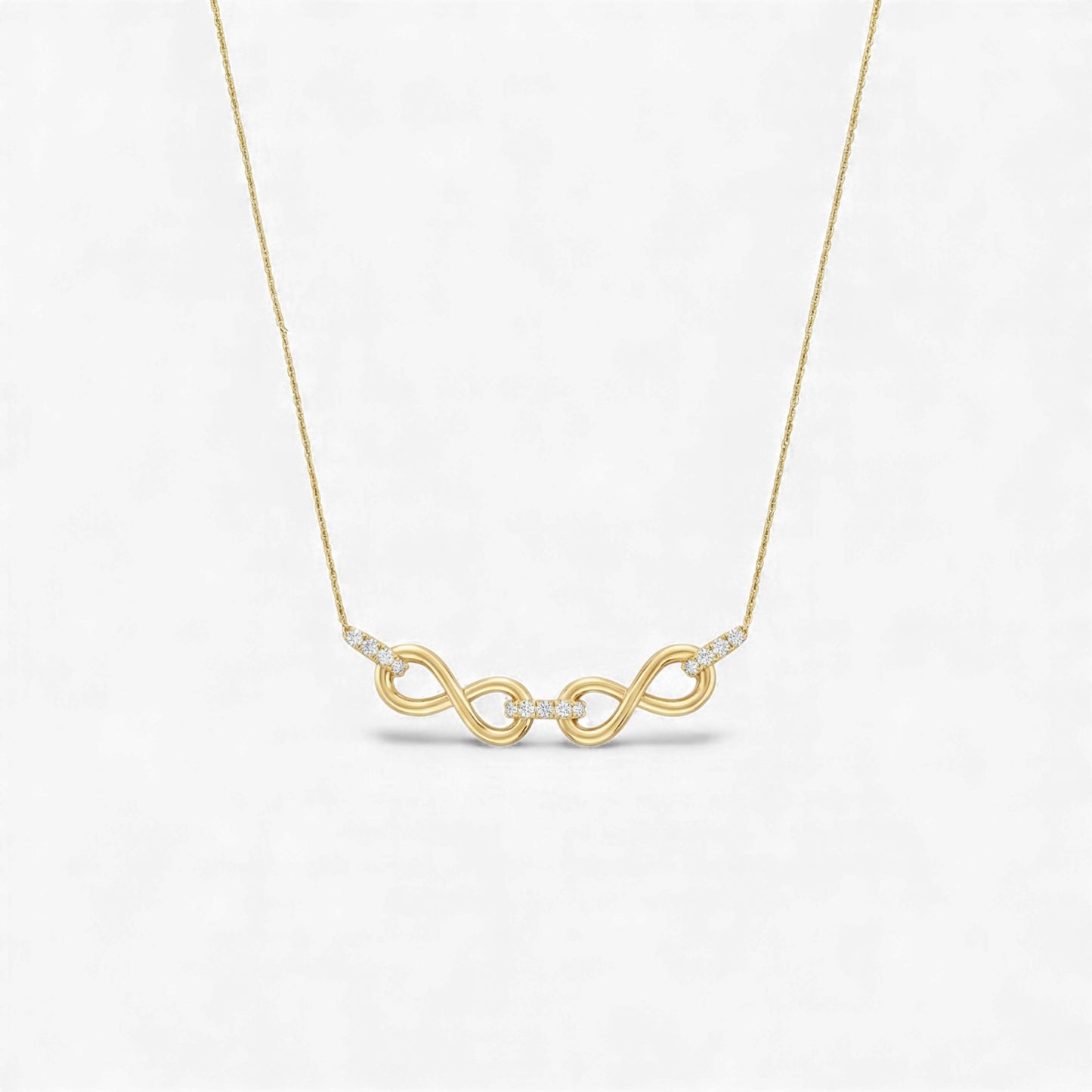 Gold necklace with a double infinity symbol pendant on a light gray background