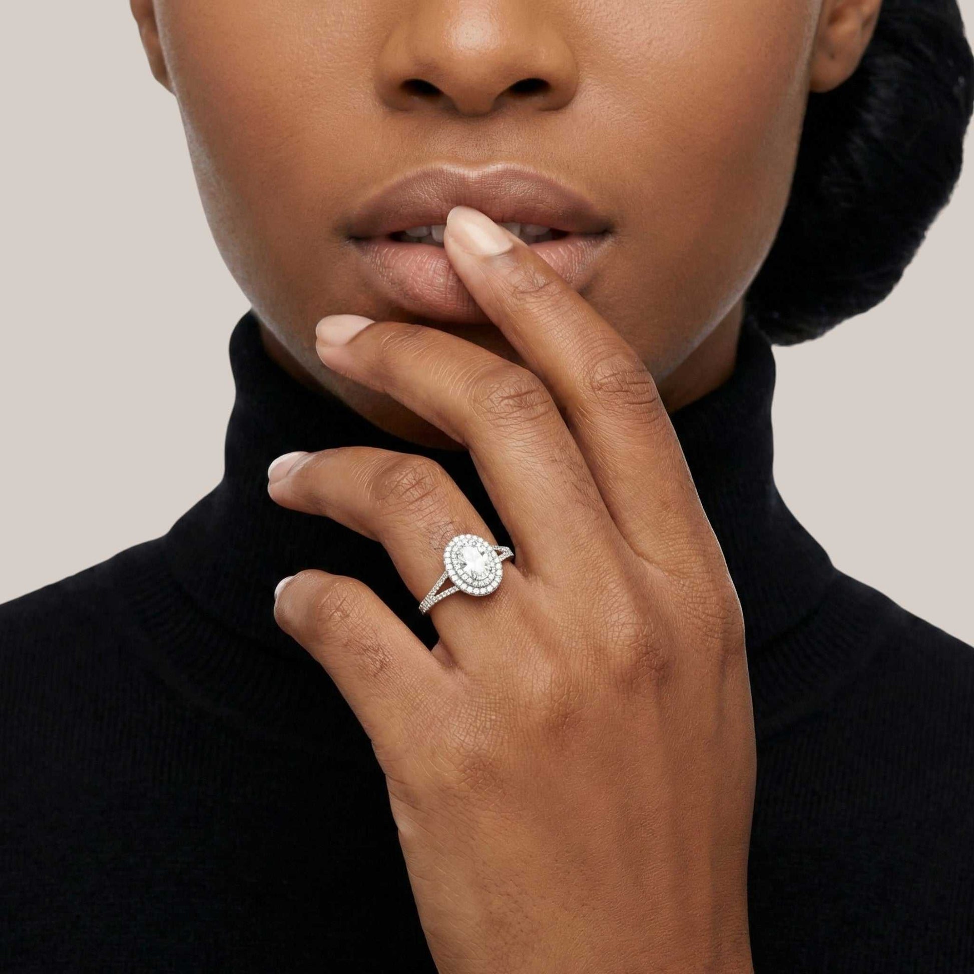 Woman wearing a diamond ring on her finger against a neutral background