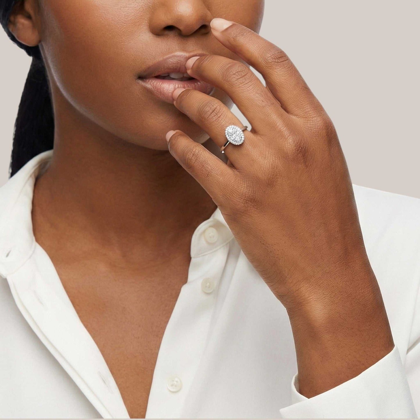 Woman wearing a diamond ring on her finger, with a neutral background