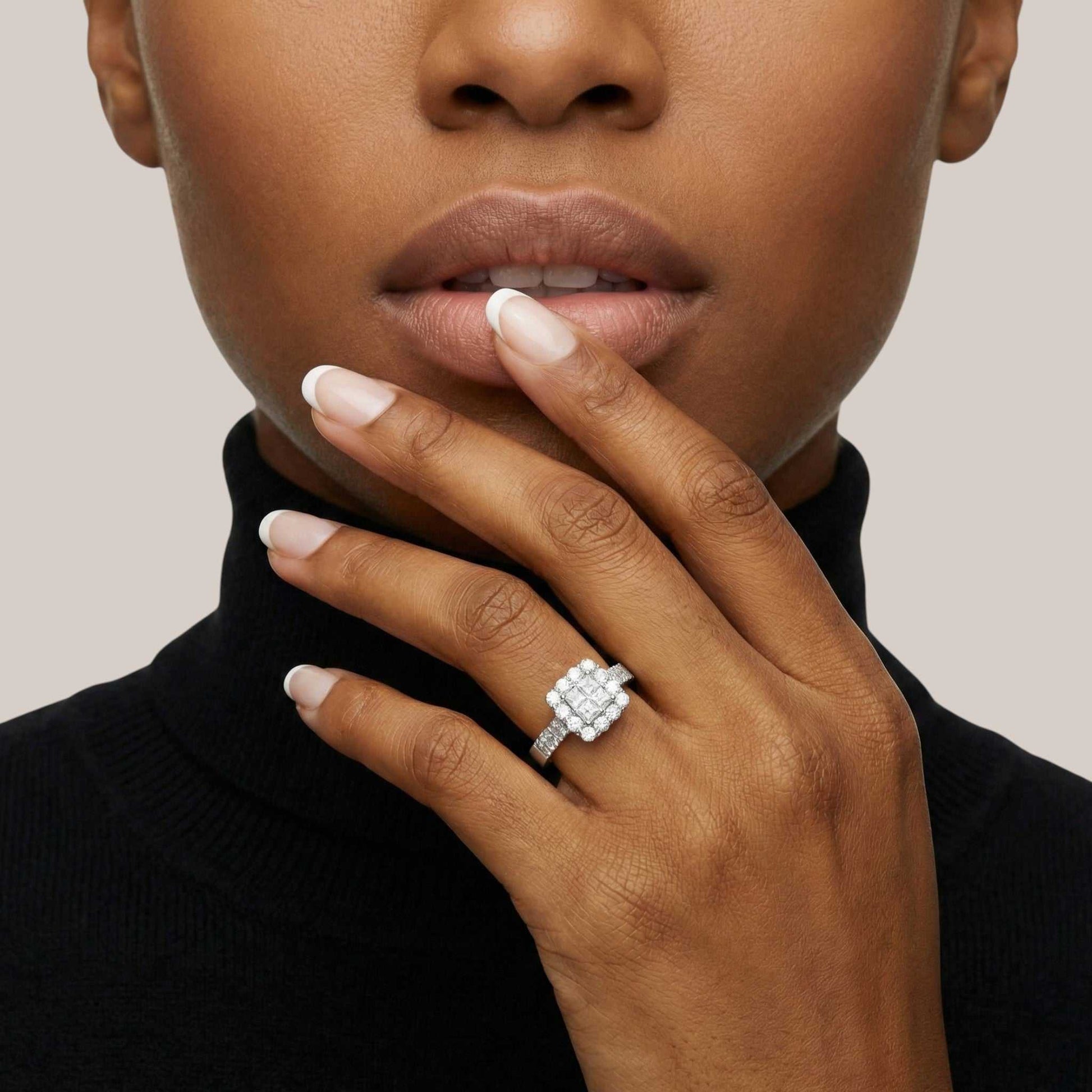 Close-up of a person wearing a diamond ring on a neutral background