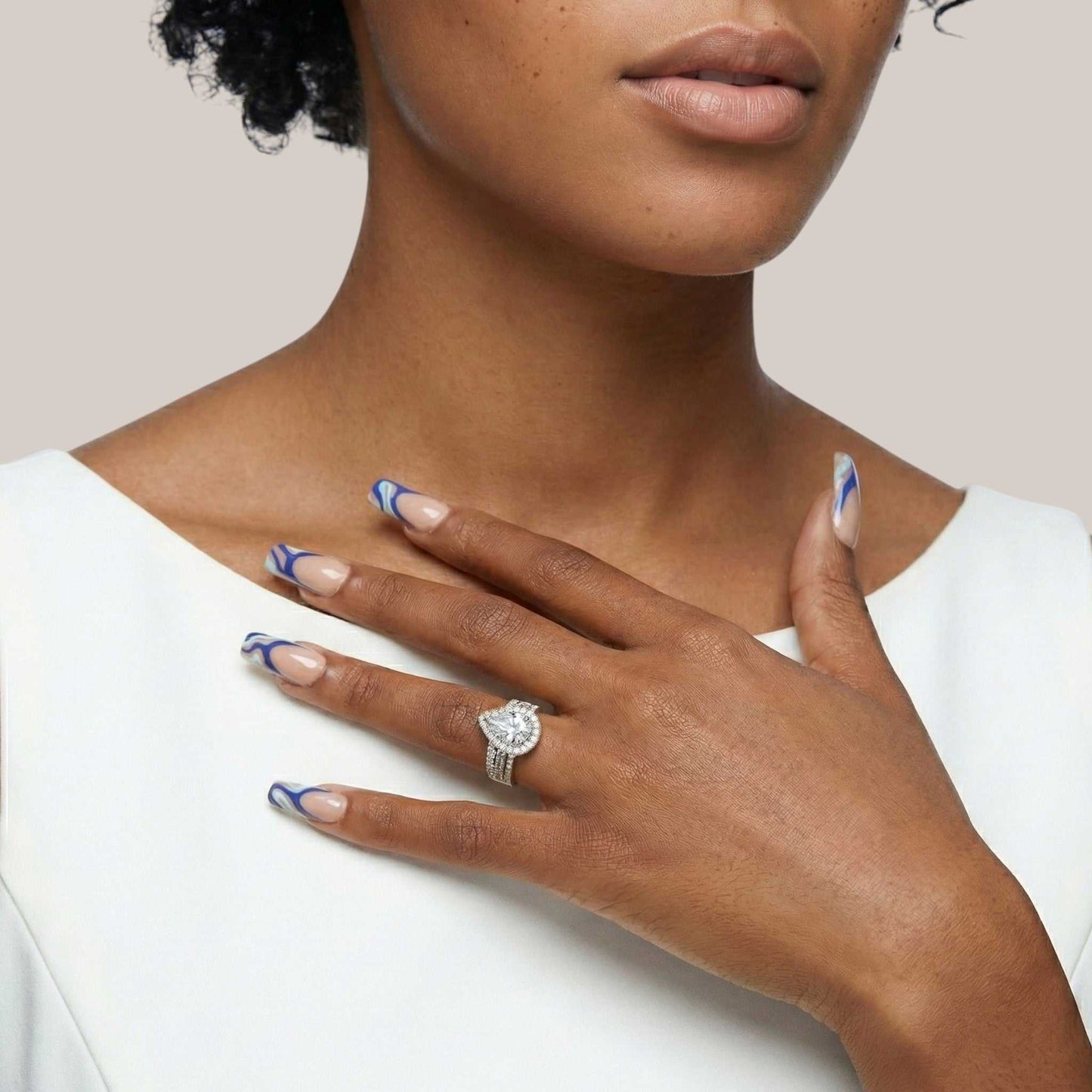 Close-up of a woman's hand wearing a diamond ring with a plain background