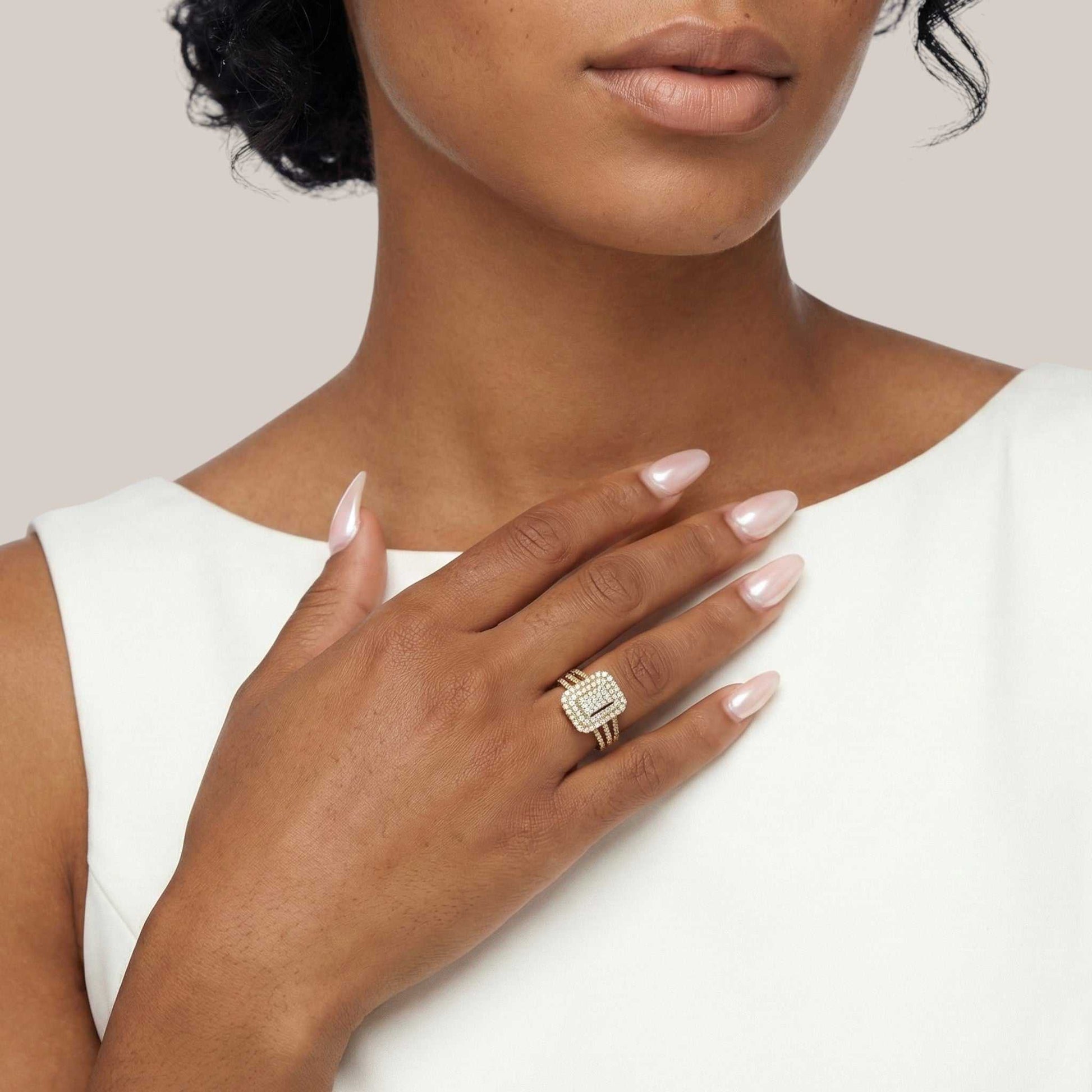 Woman wearing a gold ring with a diamond on a plain background