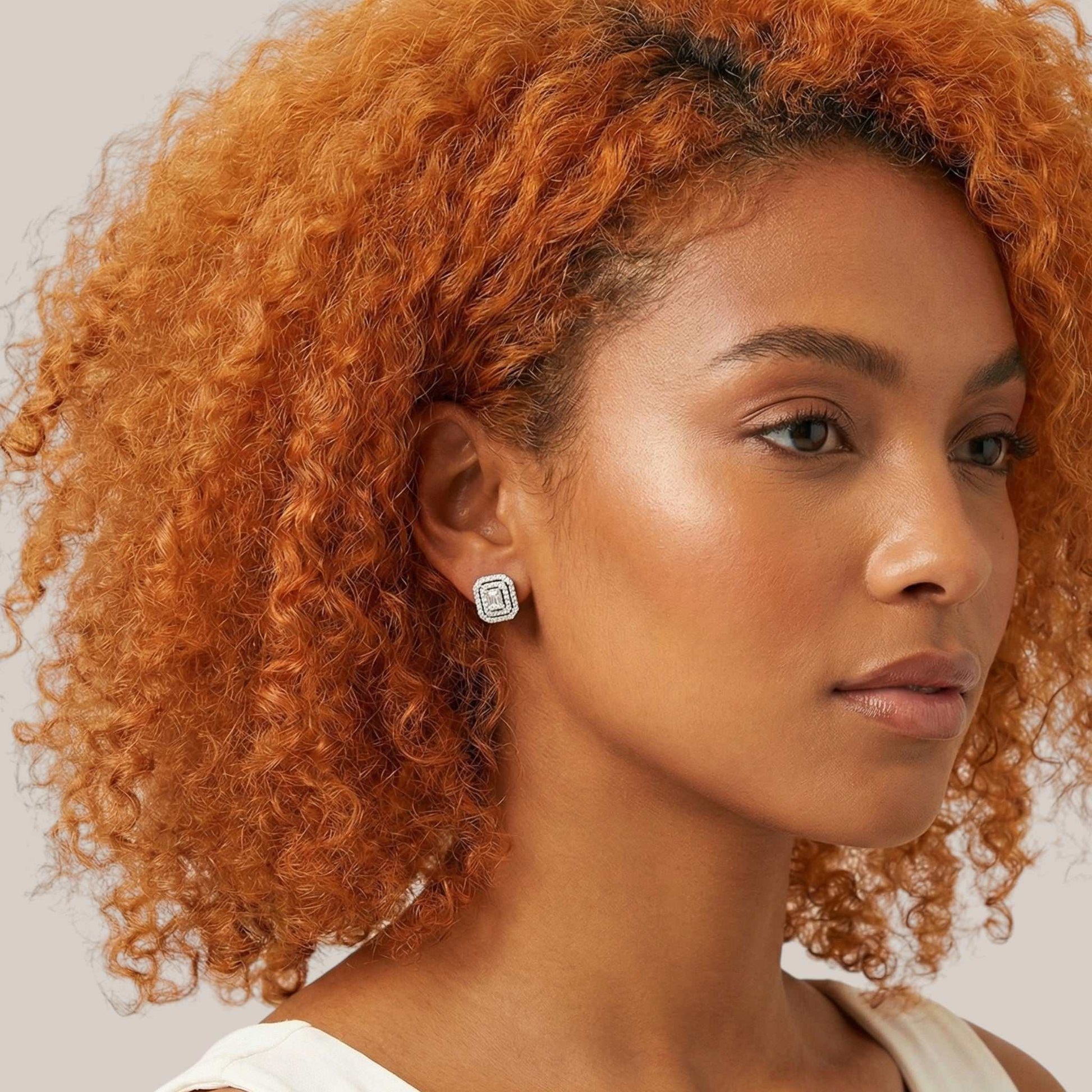 Woman with curly orange hair wearing a white top against a neutral background