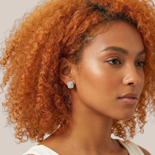 Woman with curly orange hair wearing a white top against a neutral background