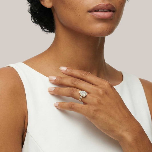 Woman wearing a gold ring with a heart-shaped diamond on a plain background