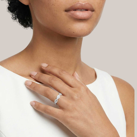 Close-up of a woman's hand wearing a diamond ring on a neutral background