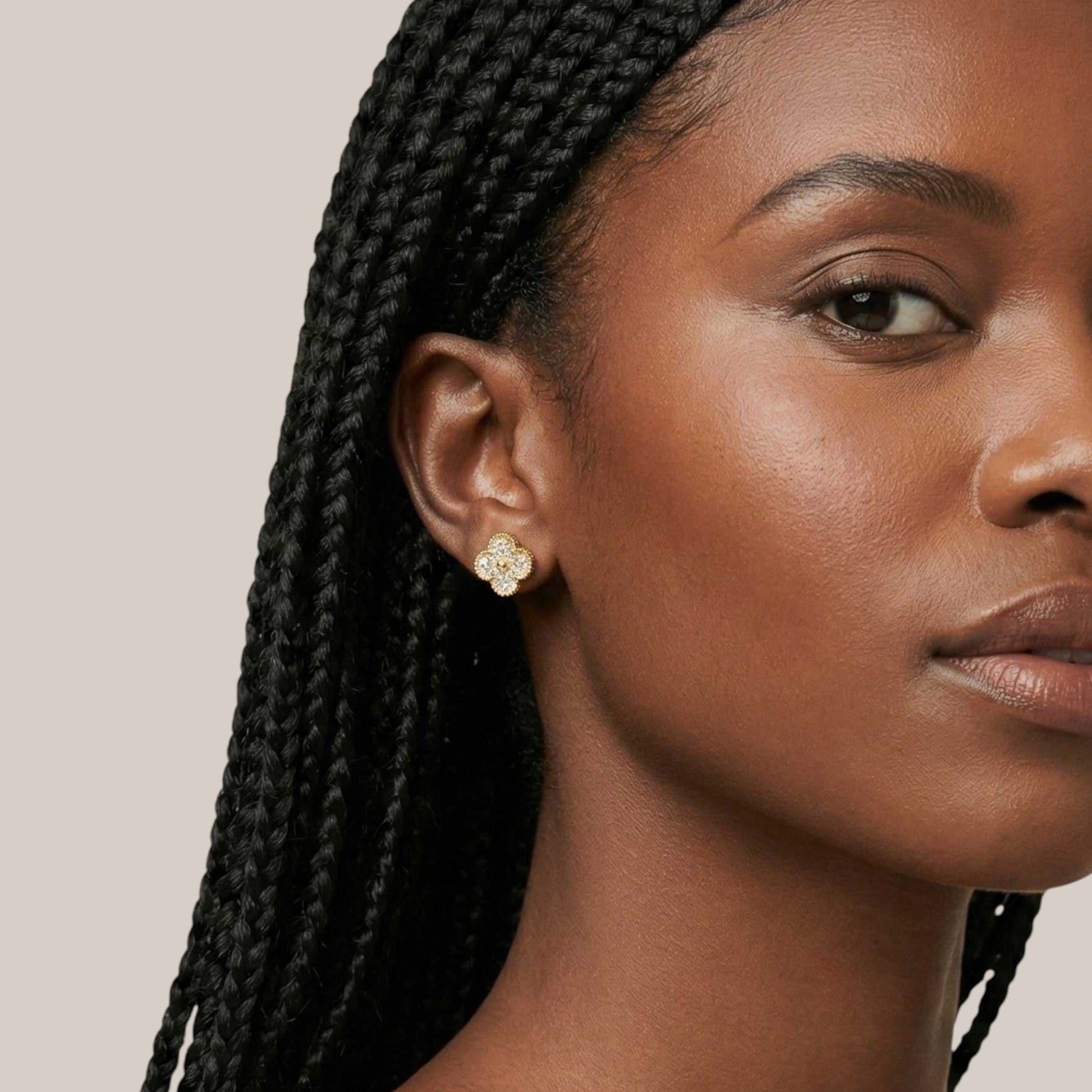 Close-up of a woman with braided hair wearing a floral earring on a beige background