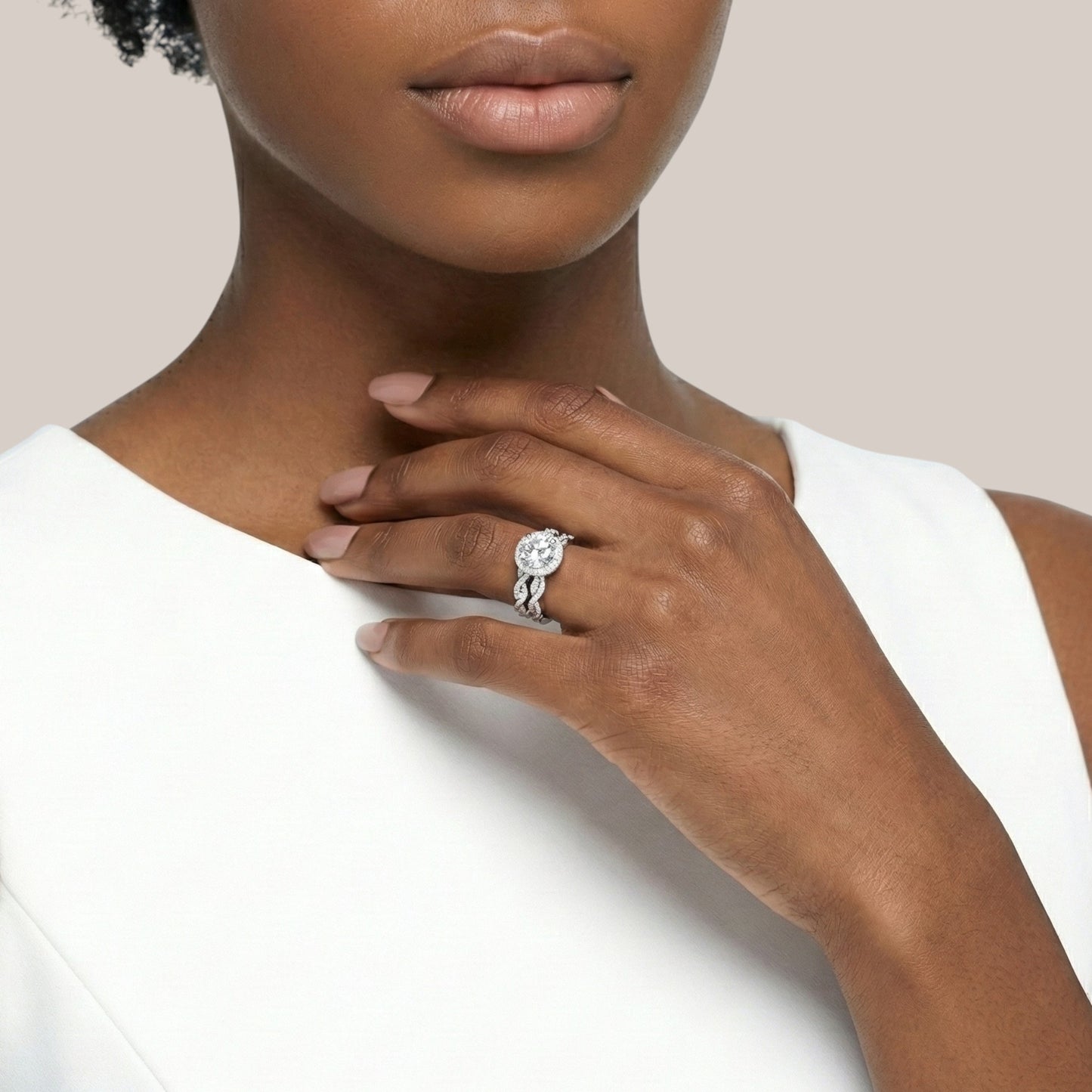 Woman wearing a silver ring with a diamond on a plain background