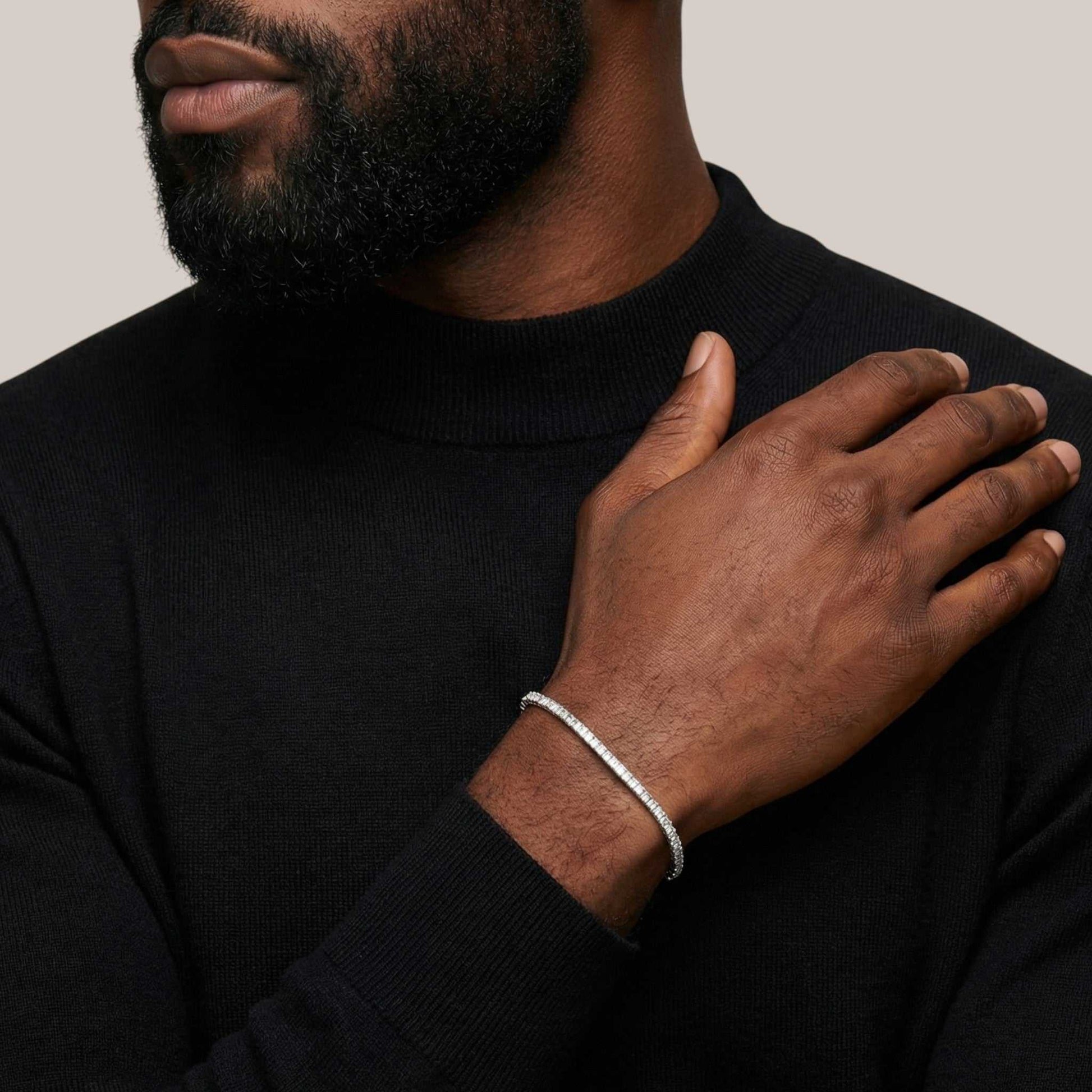 Man wearing a black turtleneck with a silver bracelet on his wrist.