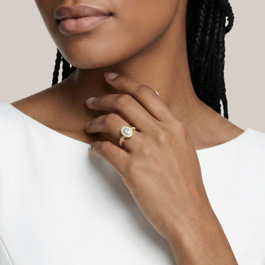 Close-up of a woman wearing a gold ring with a diamond on a plain background