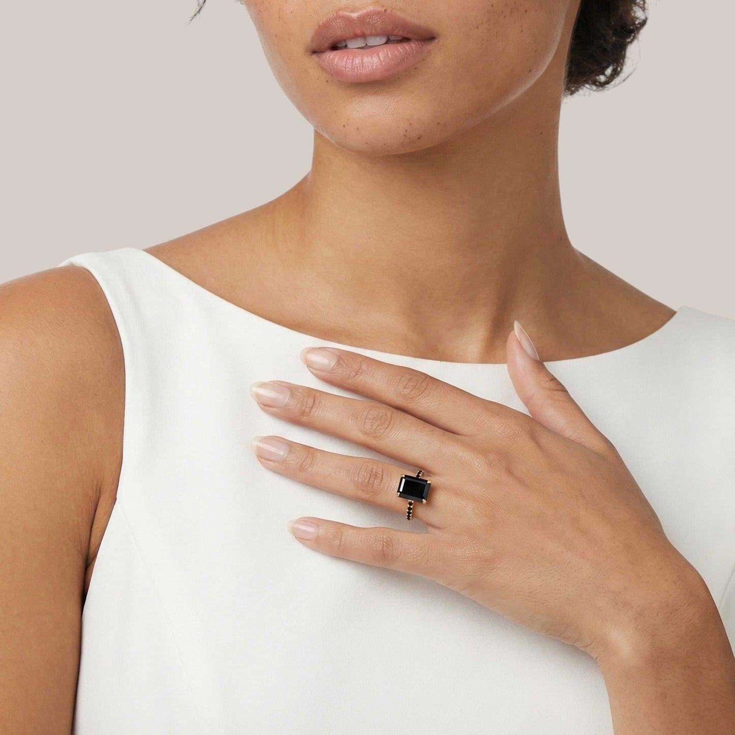 Woman wearing a black ring on her hand with a white background