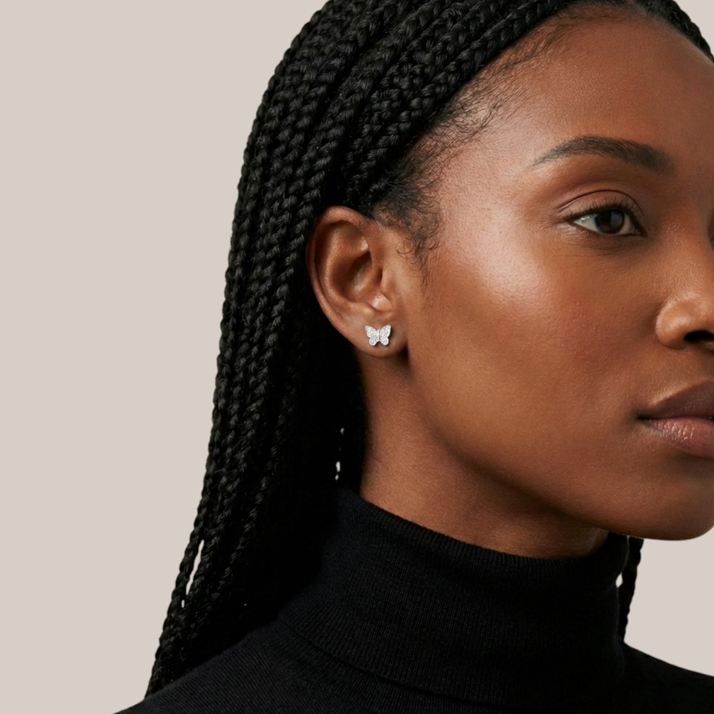 Close-up of a woman wearing butterfly earrings with a neutral background