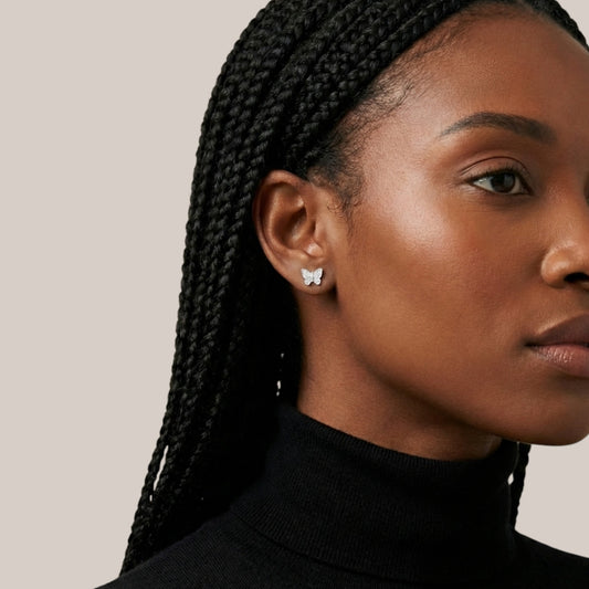 Close-up of a woman wearing butterfly earrings with a neutral background