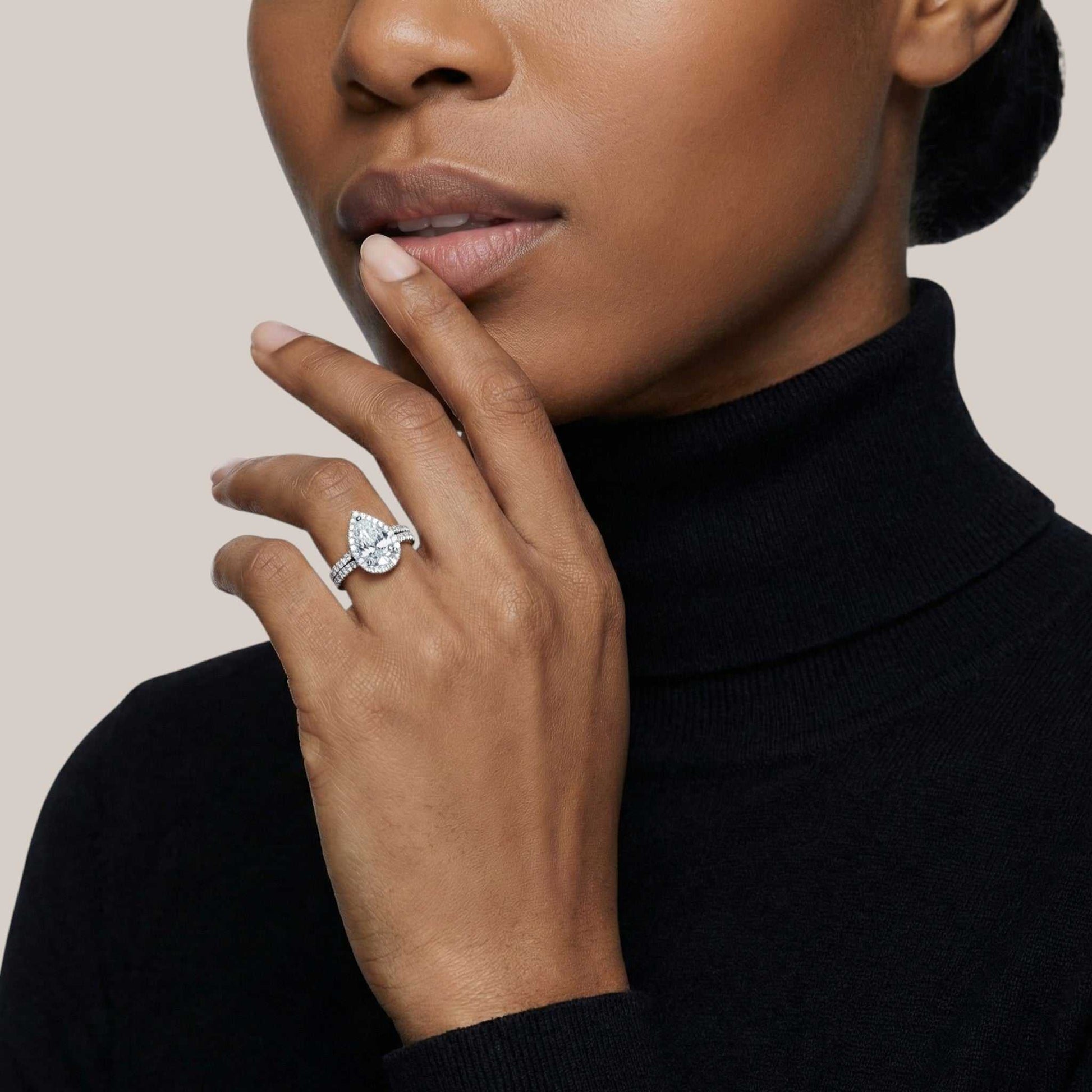 Woman wearing a diamond ring on her finger against a neutral background