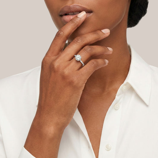 Close-up of a hand wearing a diamond ring with a neutral background