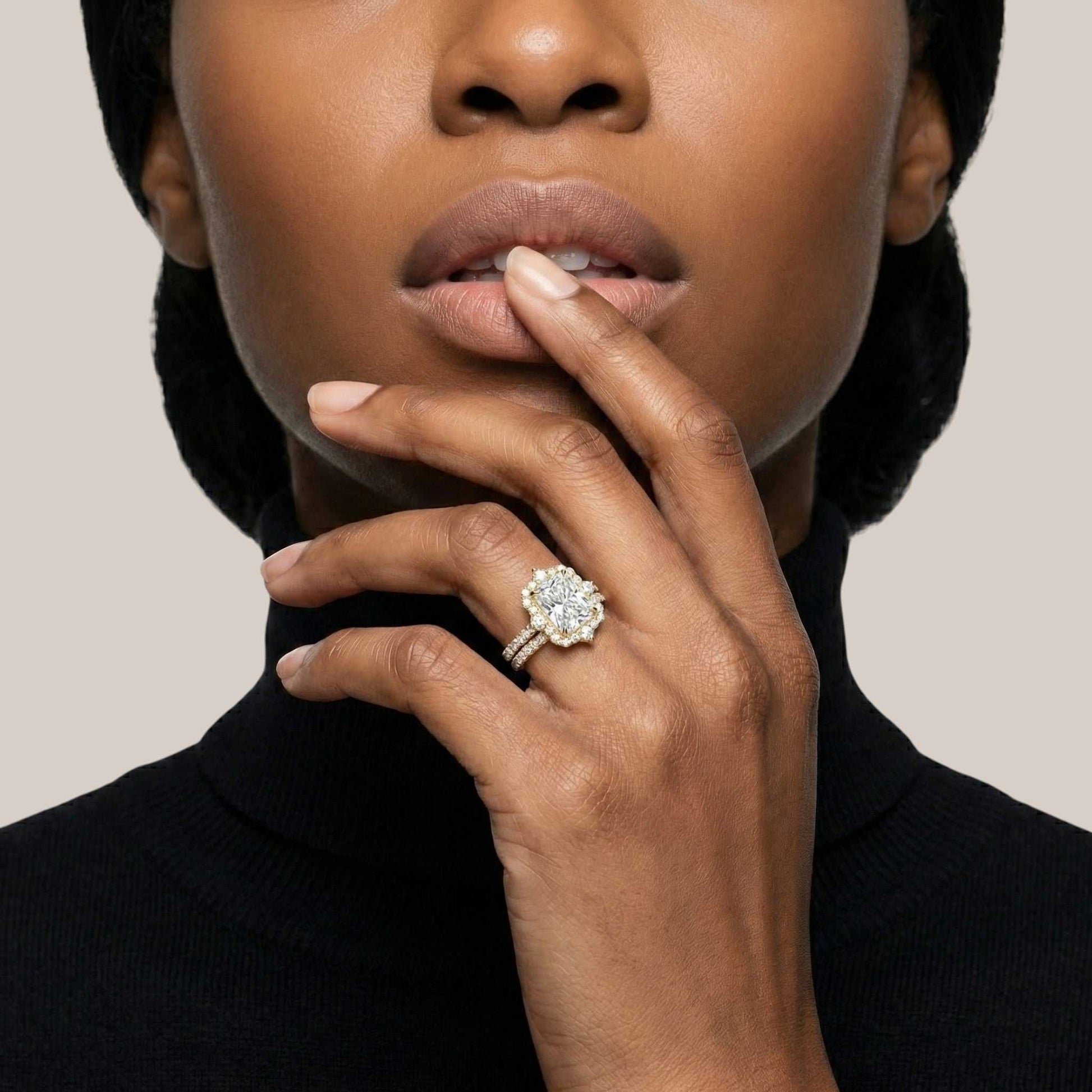 Close-up of a woman wearing a diamond ring on a neutral background
