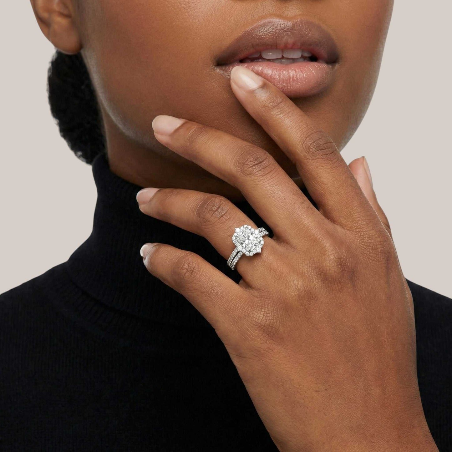 Close-up of a hand wearing a diamond ring with a neutral background