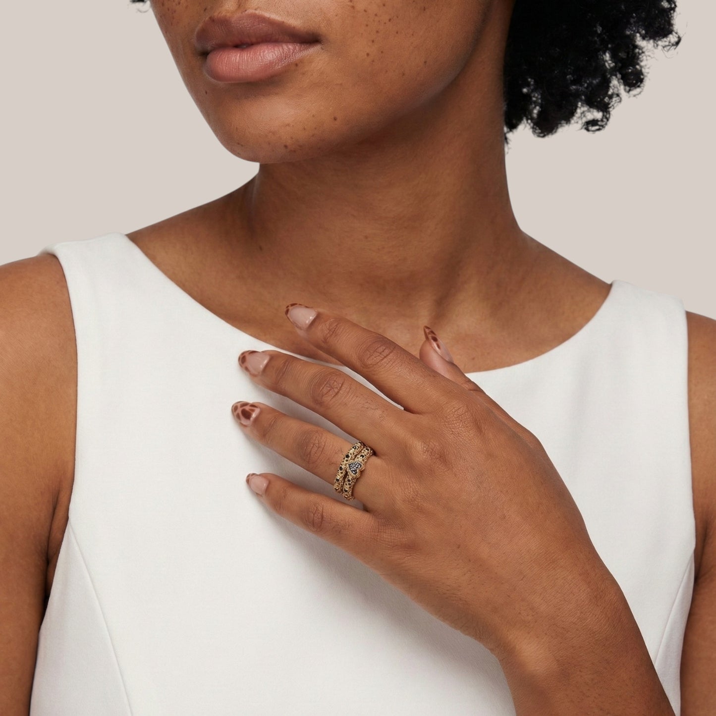 Woman wearing a gold ring on her hand against a neutral background