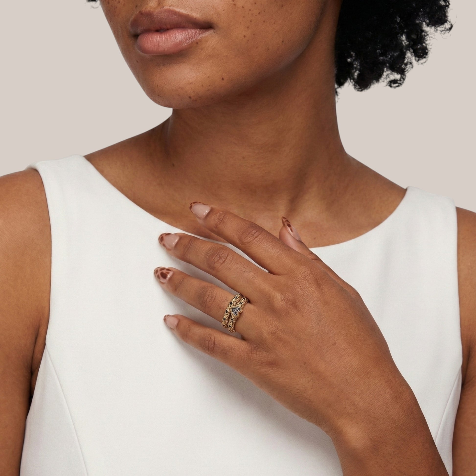 Woman wearing a gold ring on her hand against a neutral background